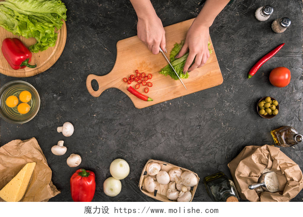 俯拍黑色背景上在案板上切碎蔬菜裁剪视图的妇女切碎蔬菜在切割板上与比萨饼成分在灰色背景 
